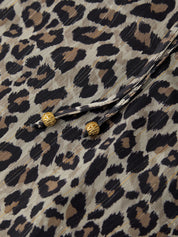 Close-up of a leopard print fabric with gold buttons.