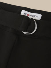 Close-up of a black skirt or dress waistband with a matching black belt and a large silver-tone metal O-ring, featuring a white interior label that reads 89th & MADISON.