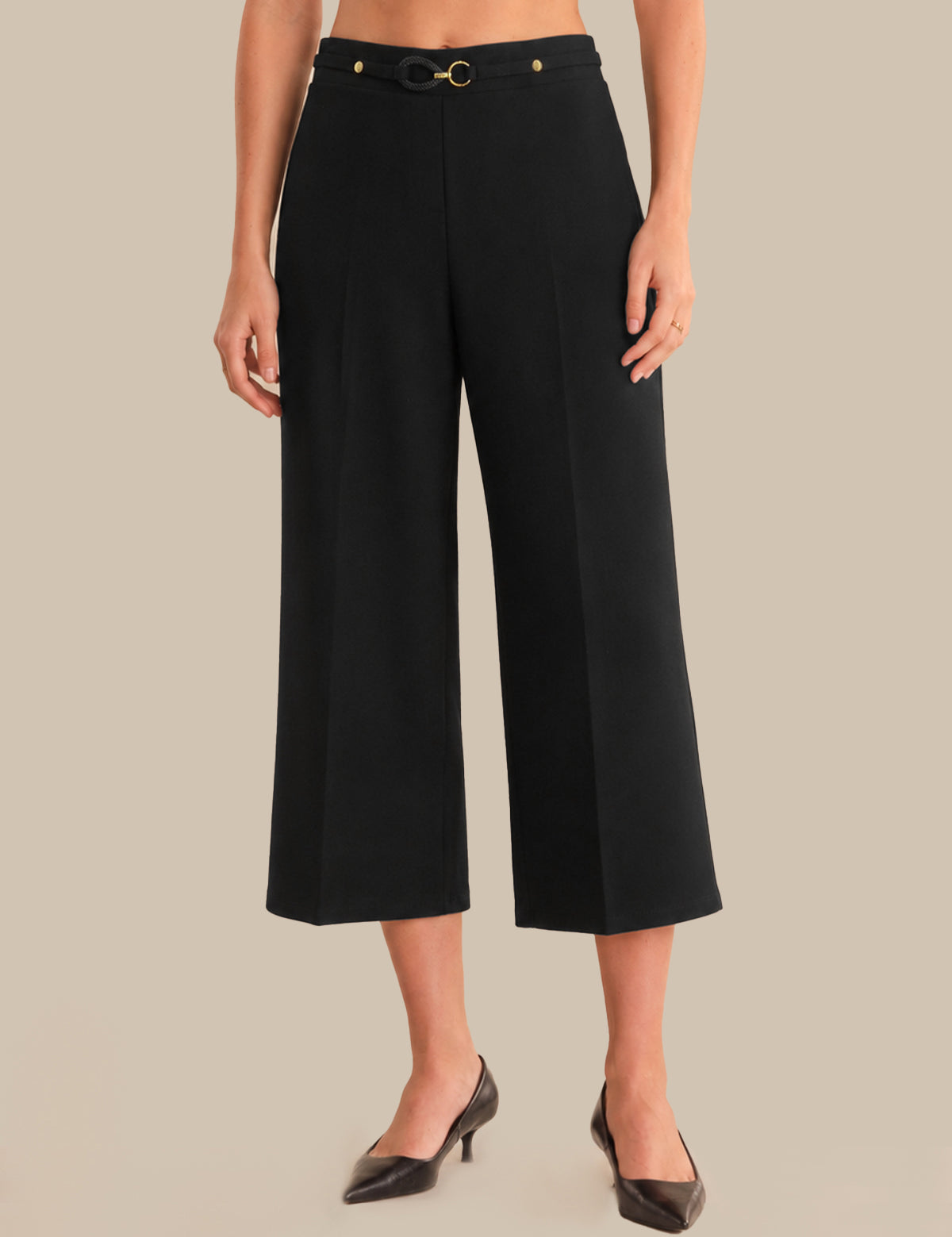 Person wearing black wide-leg pants with a belt on a beige background