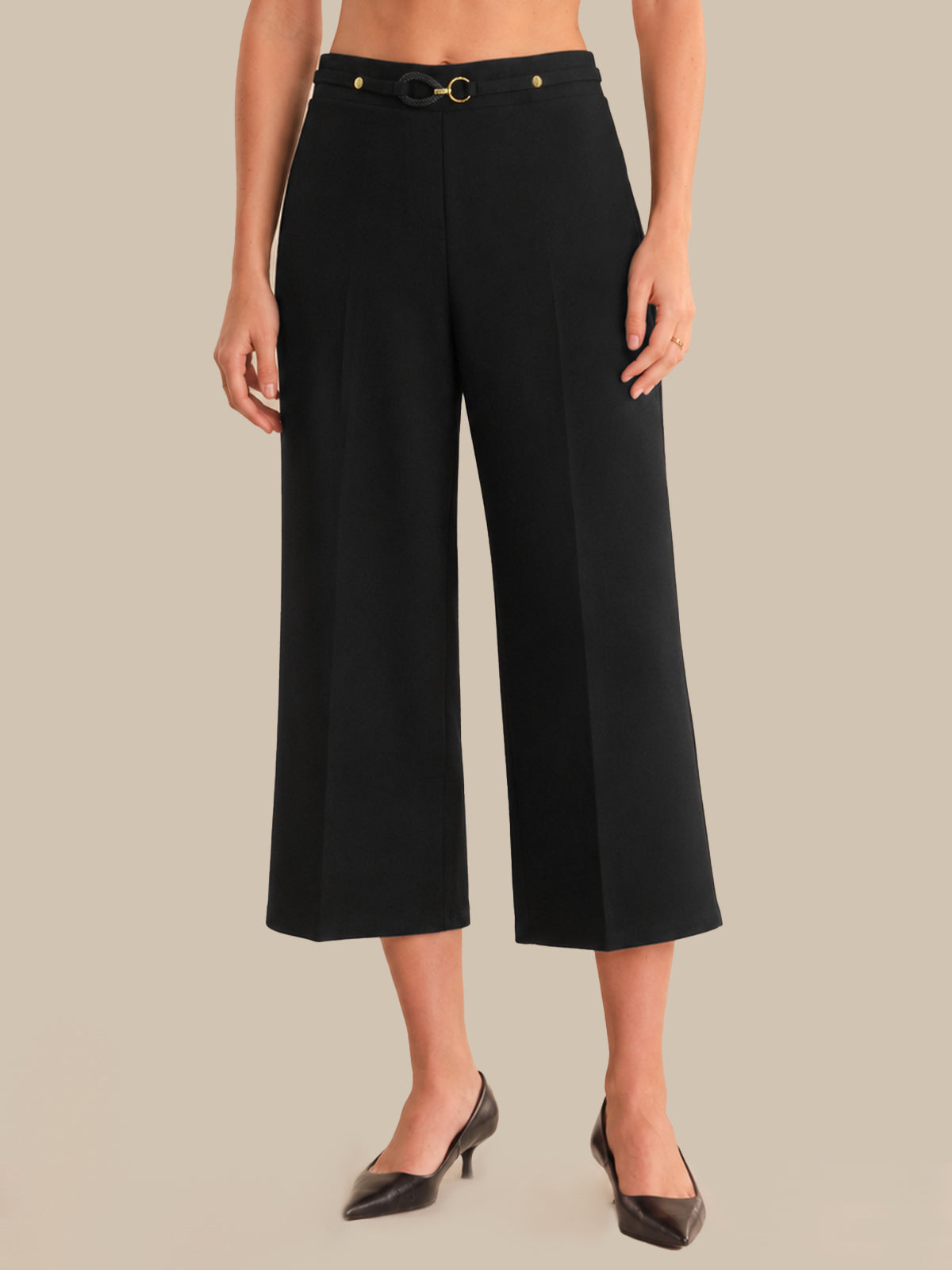 Person wearing black wide-leg pants with a belt on a beige background