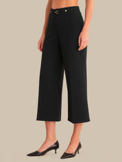 Person wearing black wide-leg pants on a beige background