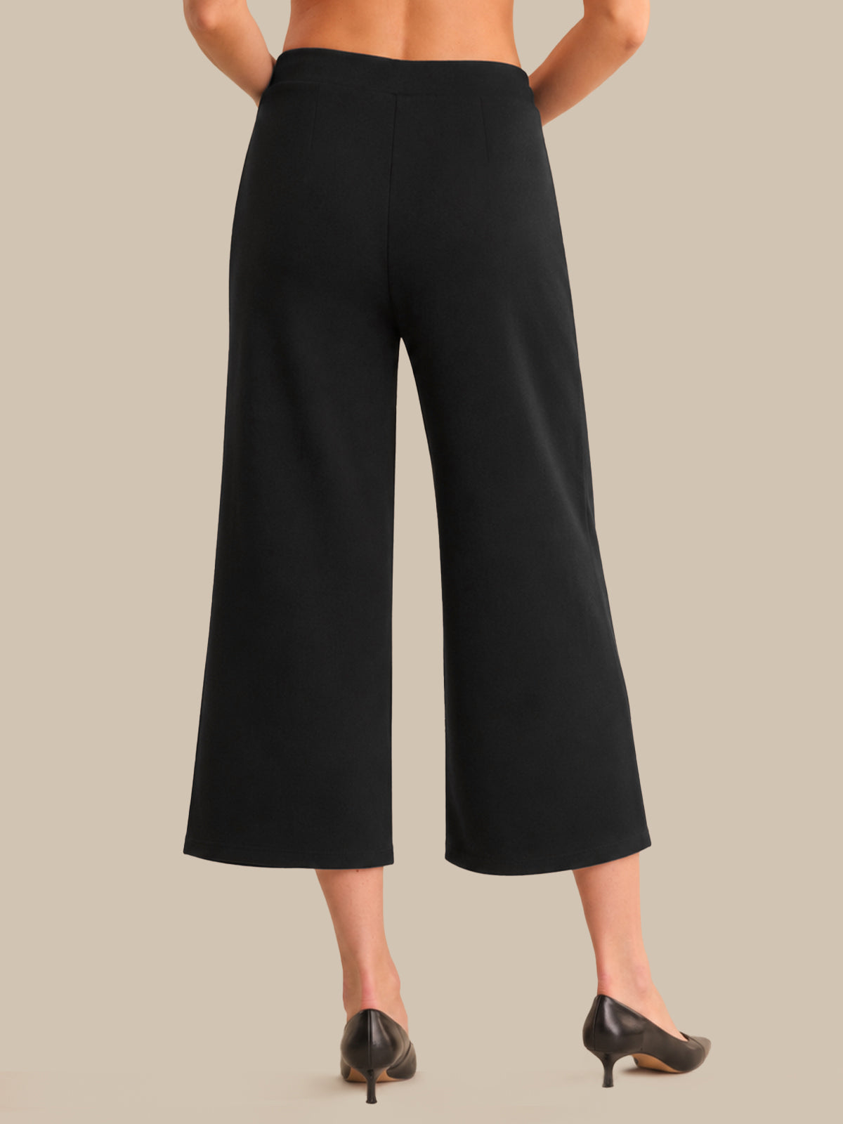 Black wide-leg pants worn by a person on a beige background