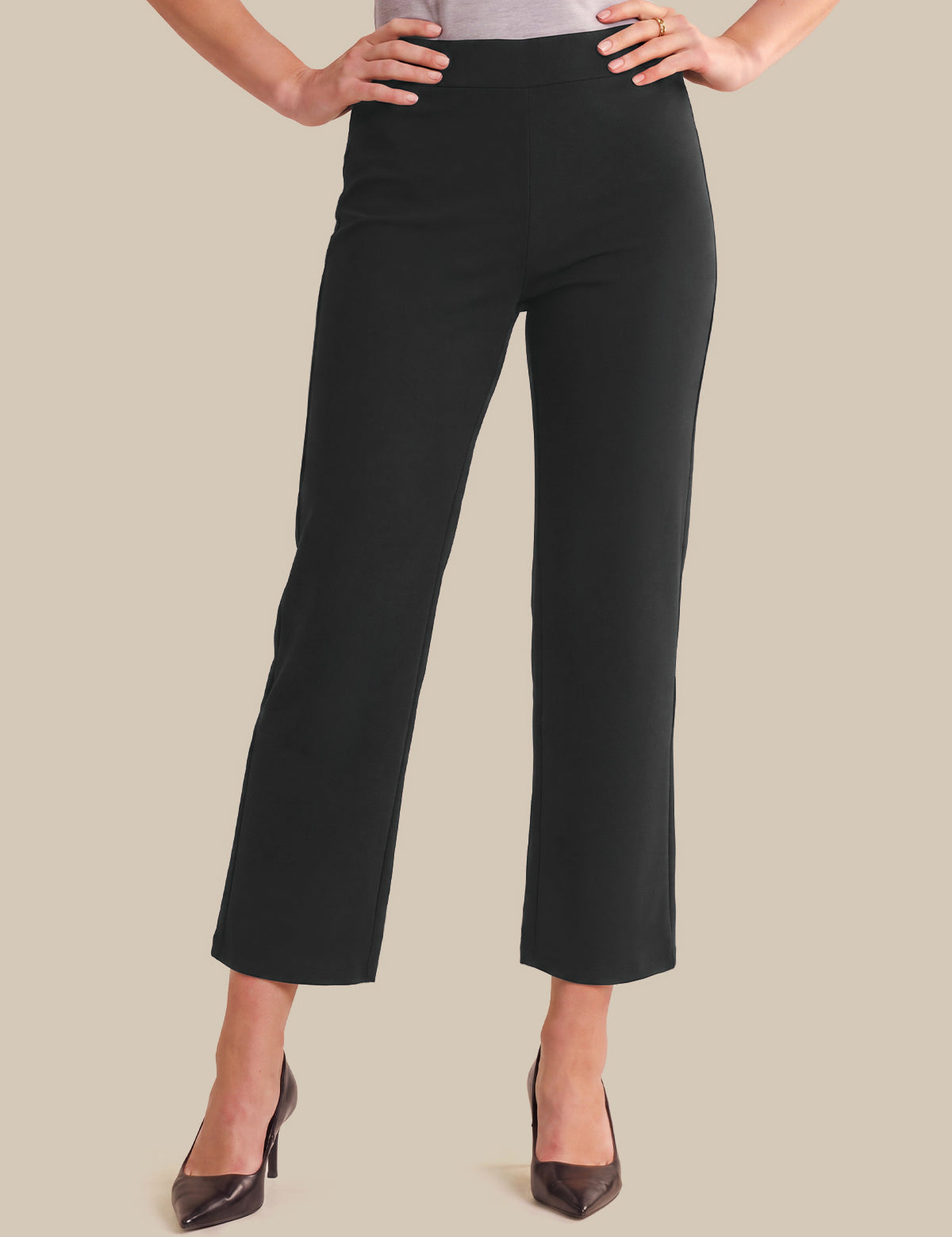 Black cropped wide-leg pants shown on a model from the waist down, paired with dark brown pointed-toe heels against a solid beige background.