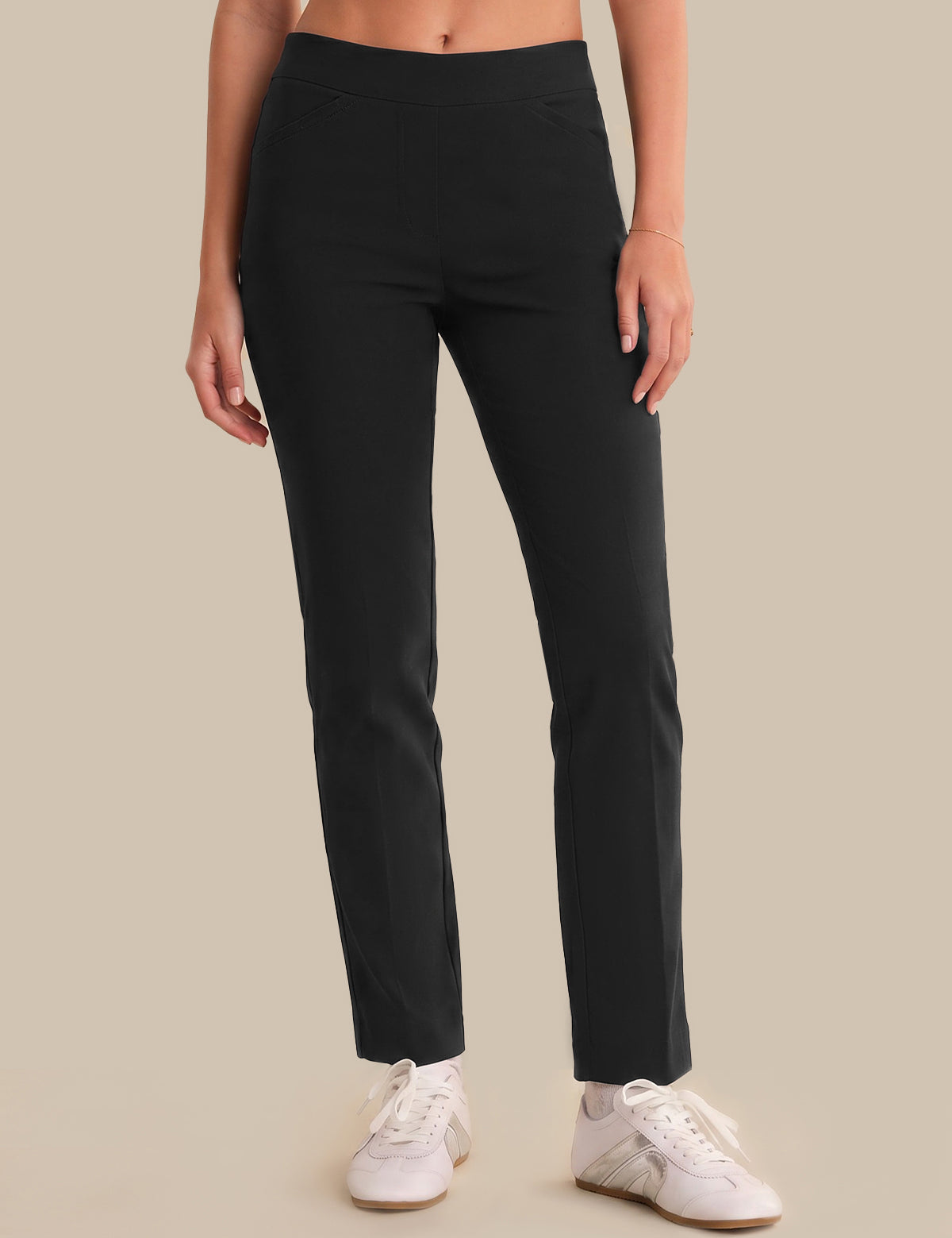 Person wearing black pants and white sneakers on a beige background