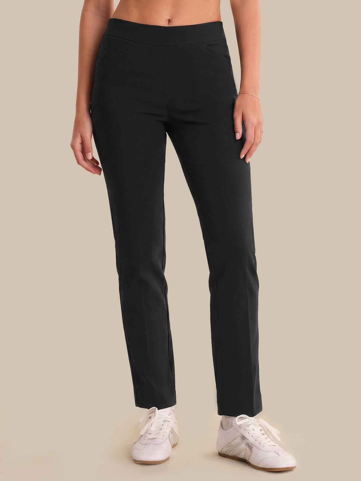 Person wearing black pants and white sneakers on a beige background