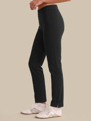 Person wearing black pants with white sneakers on a beige background