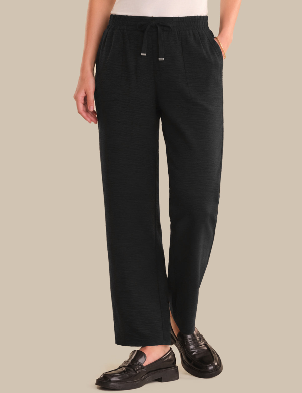 Person wearing black pants on a beige background