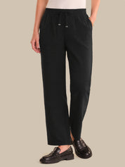 Person wearing black pants on a beige background