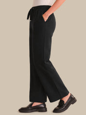 Person wearing black pants on a beige background