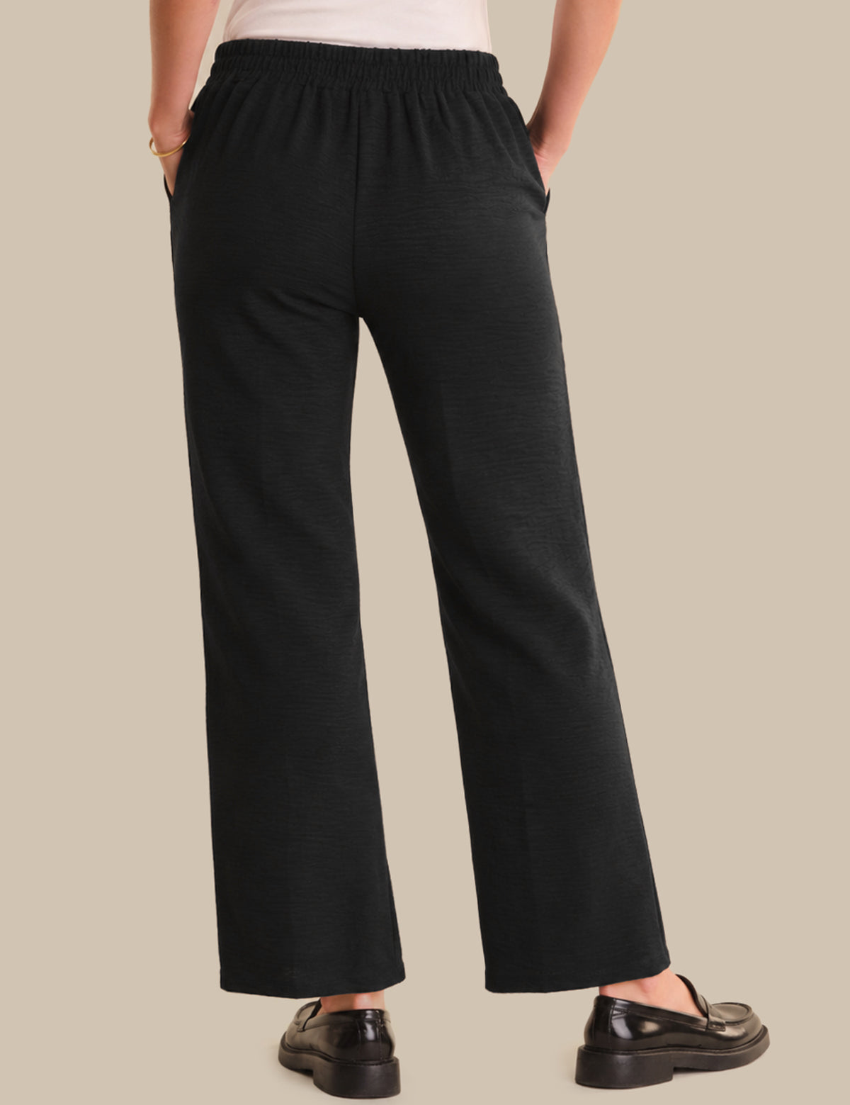 Person wearing black pants on a beige background