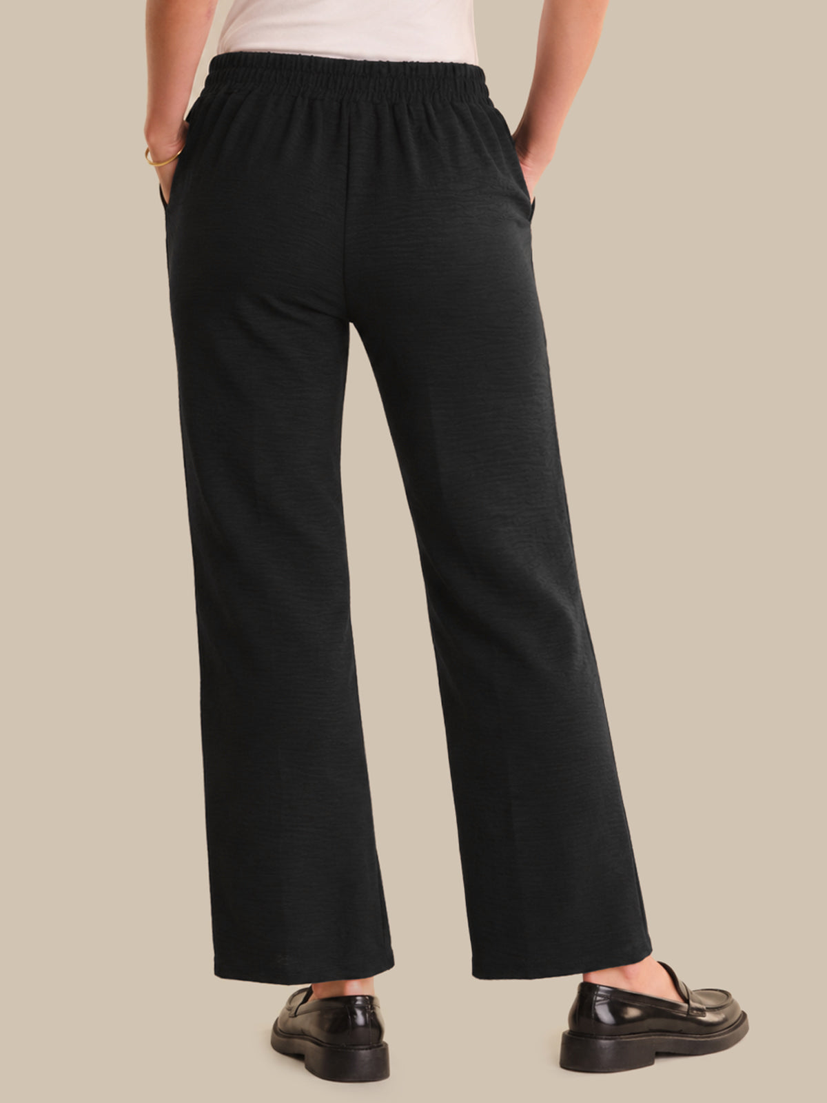 Person wearing black pants on a beige background
