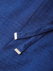 A close-up of a textured royal blue fabric, likely a wool or cashmere sweater, featuring two small, polished silver rectangular bar pins attached near the fold.