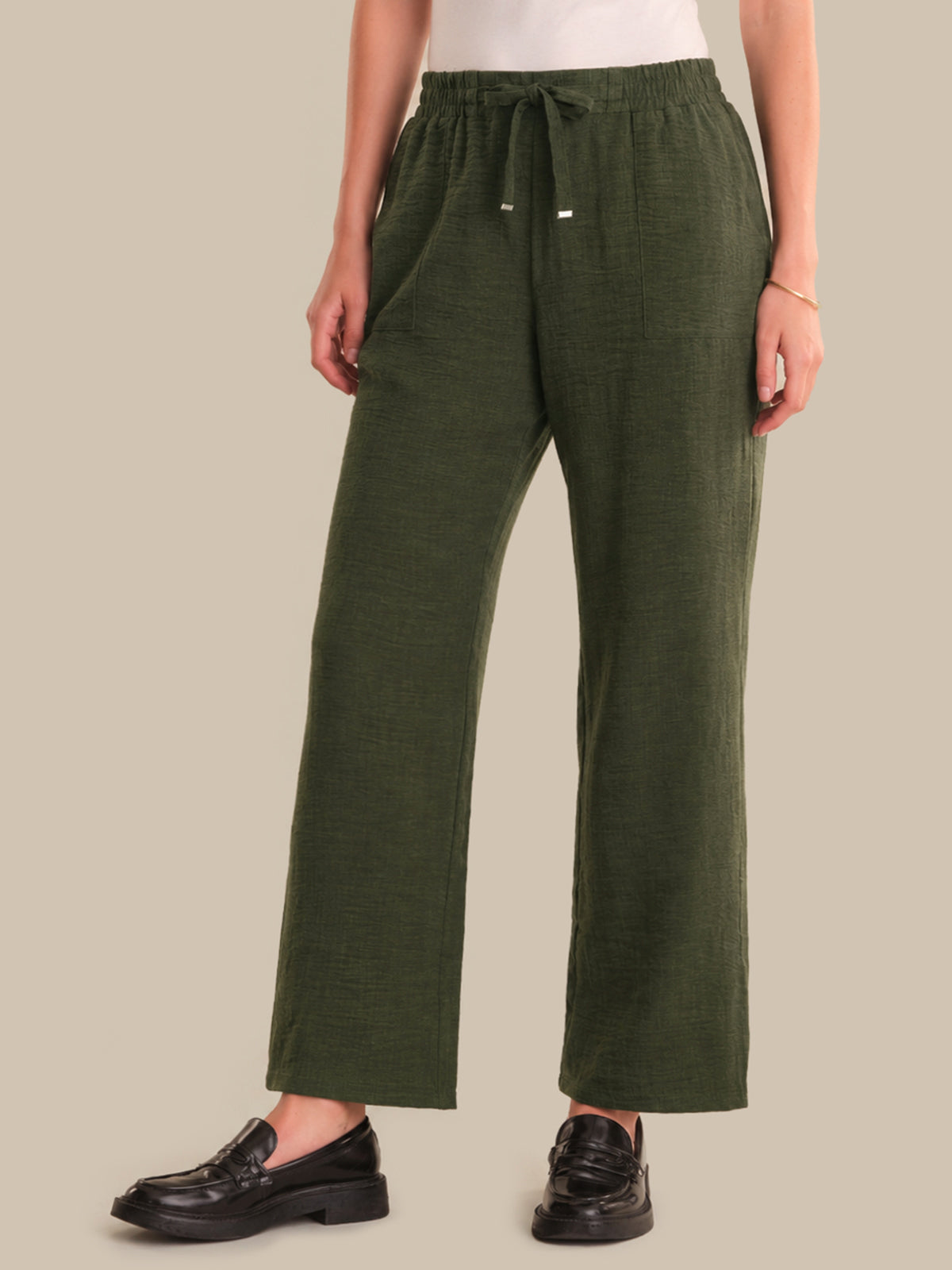 Person wearing green pants on a beige background