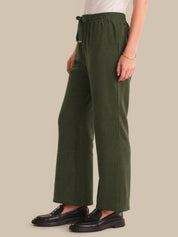 Person wearing green pants and black shoes on a plain background