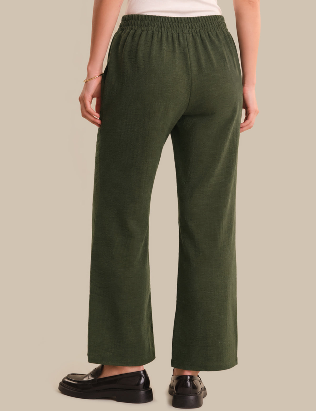 Person wearing green pants on a beige background