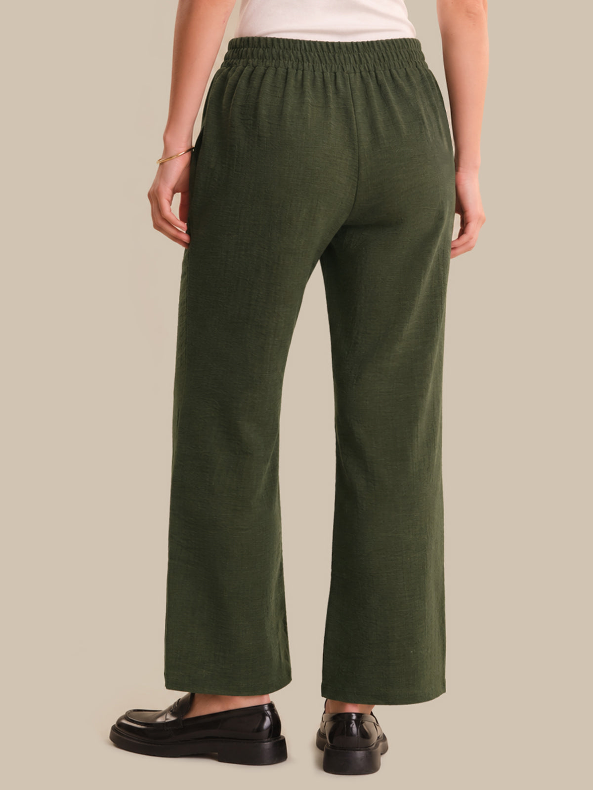 Person wearing green pants on a beige background