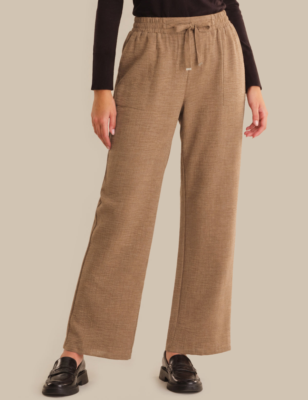 Person wearing brown wide-leg pants on a beige background