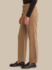 Person wearing brown ribbed knit pants on a beige background
