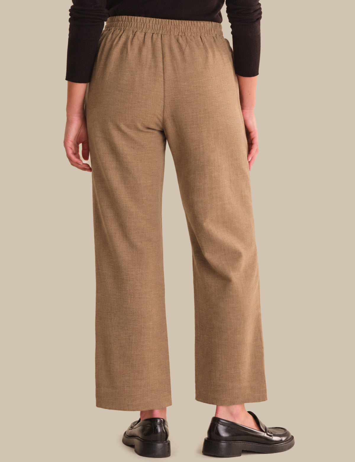 Person wearing brown wide-leg pants on a beige background