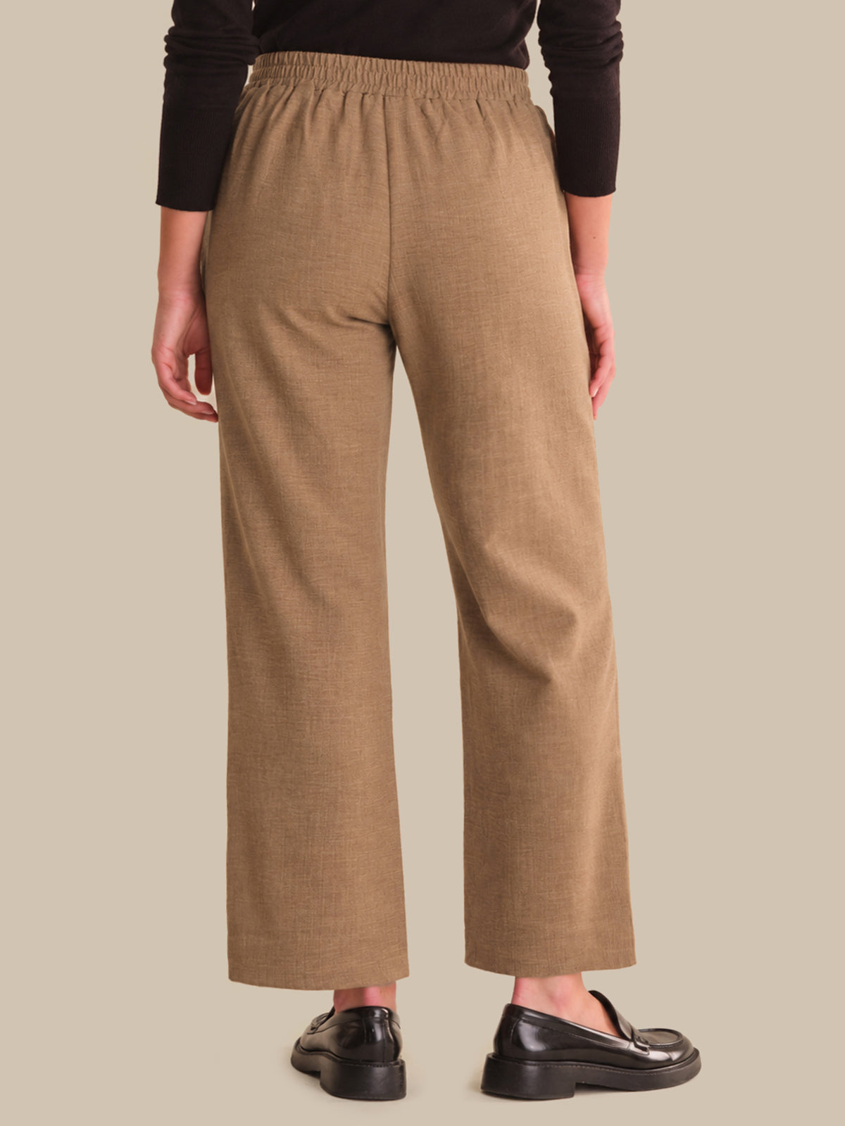 Person wearing brown wide-leg pants on a beige background
