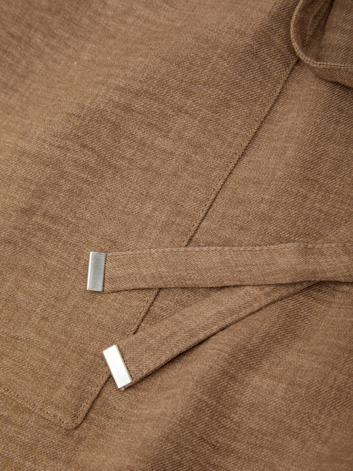 Close-up of a brown fabric with a metal clip on a plain background