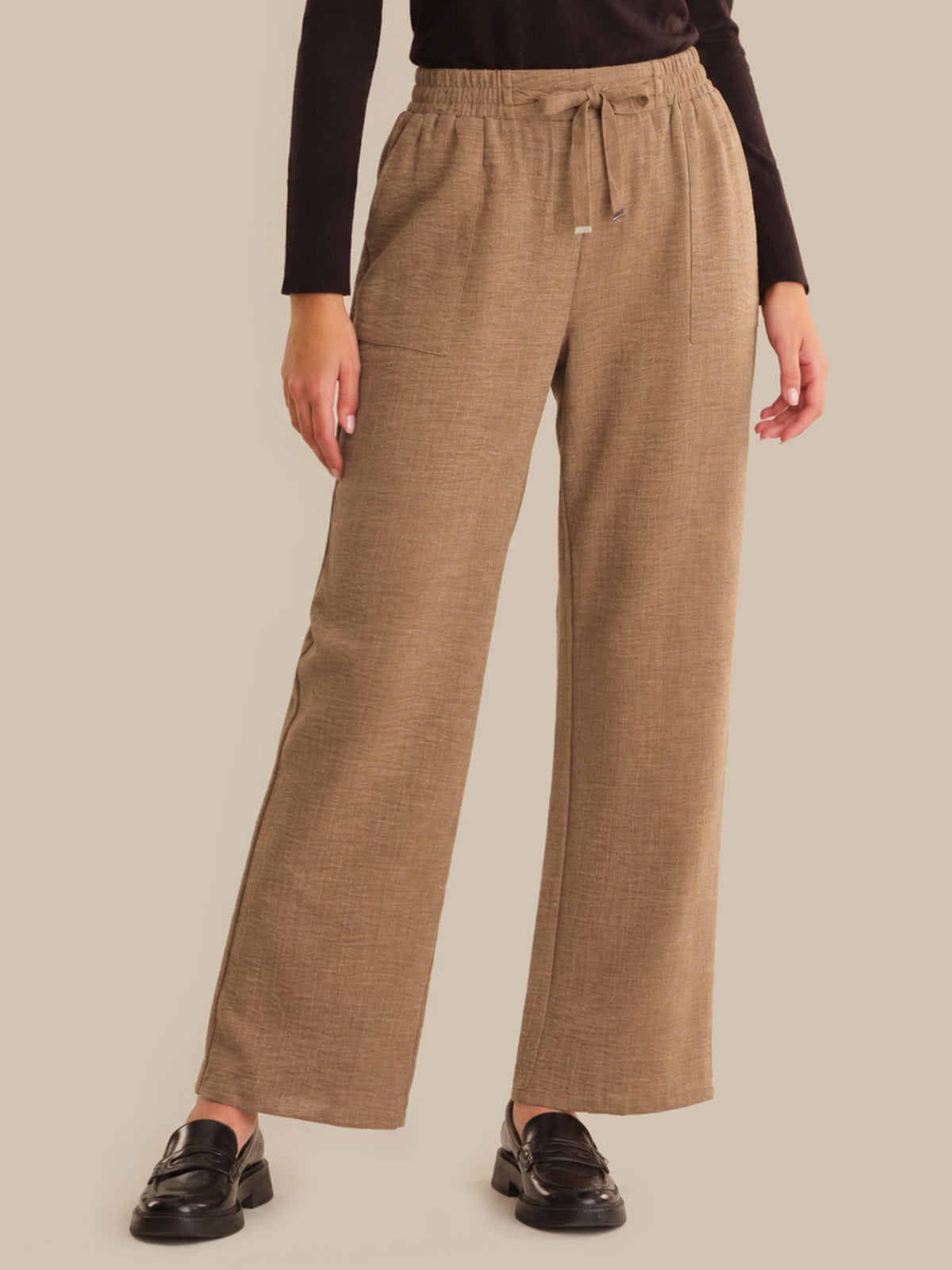 Person wearing brown wide-leg pants on a beige background