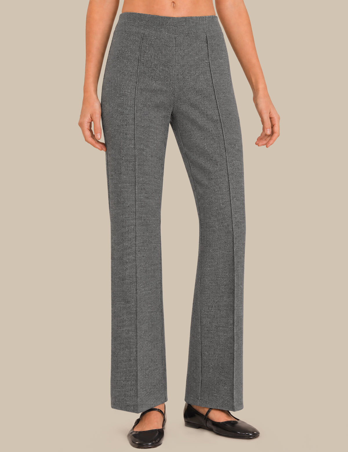 A model wearing a pair of high-waisted, wide-leg gray trousers with a subtle textured weave, paired with black flats, against a solid beige background.