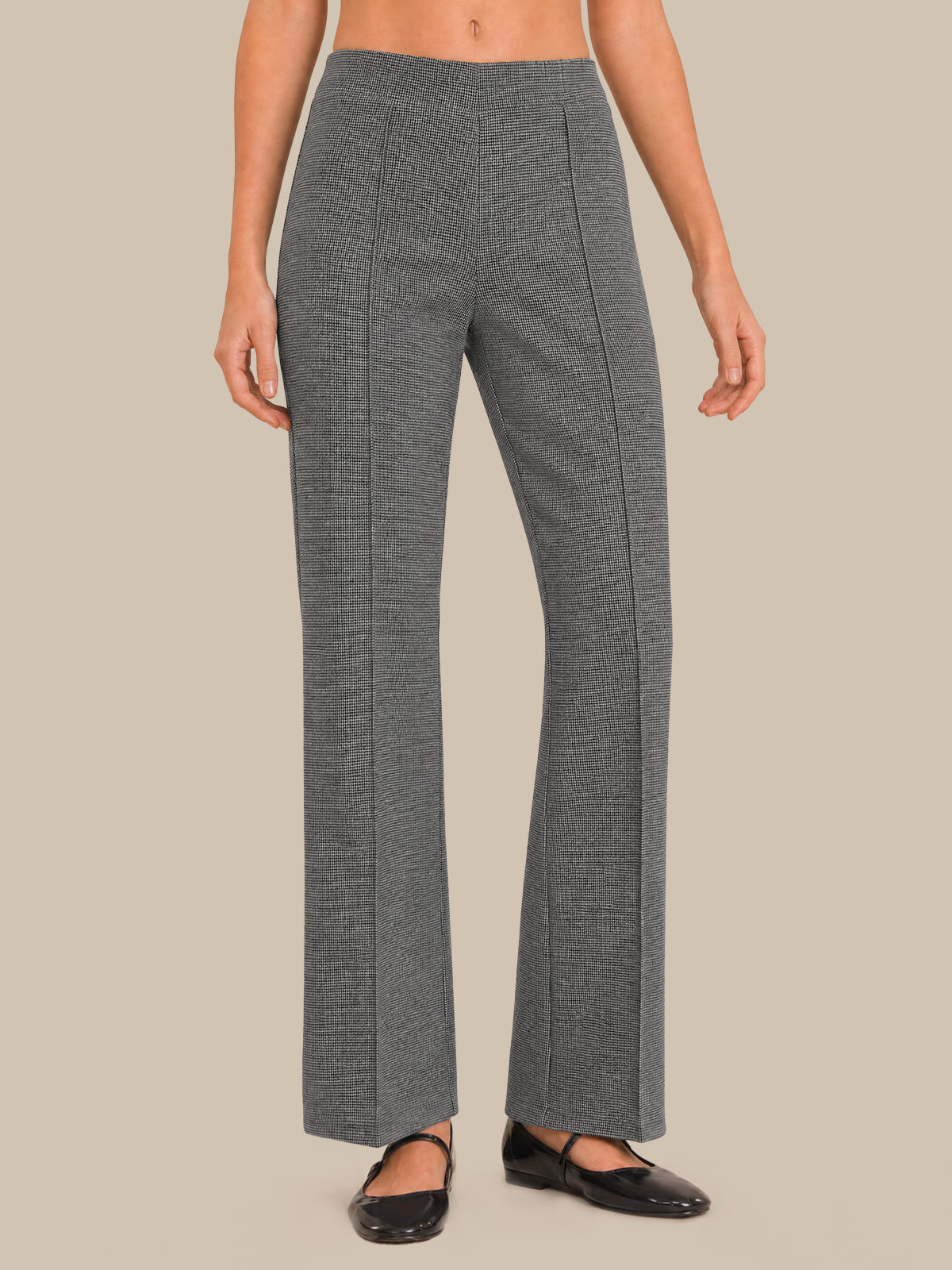 A model wearing a pair of high-waisted, wide-leg gray trousers with a subtle textured weave, paired with black flats, against a solid beige background.