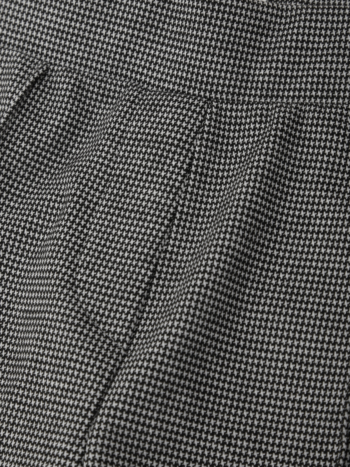 Close-up of a black and white micro-patterned fabric, showing a fine woven texture and soft folds.