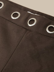 Close-up of dark brown suede-like fabric with a waistband and four silver metal grommets, set against a light beige background.