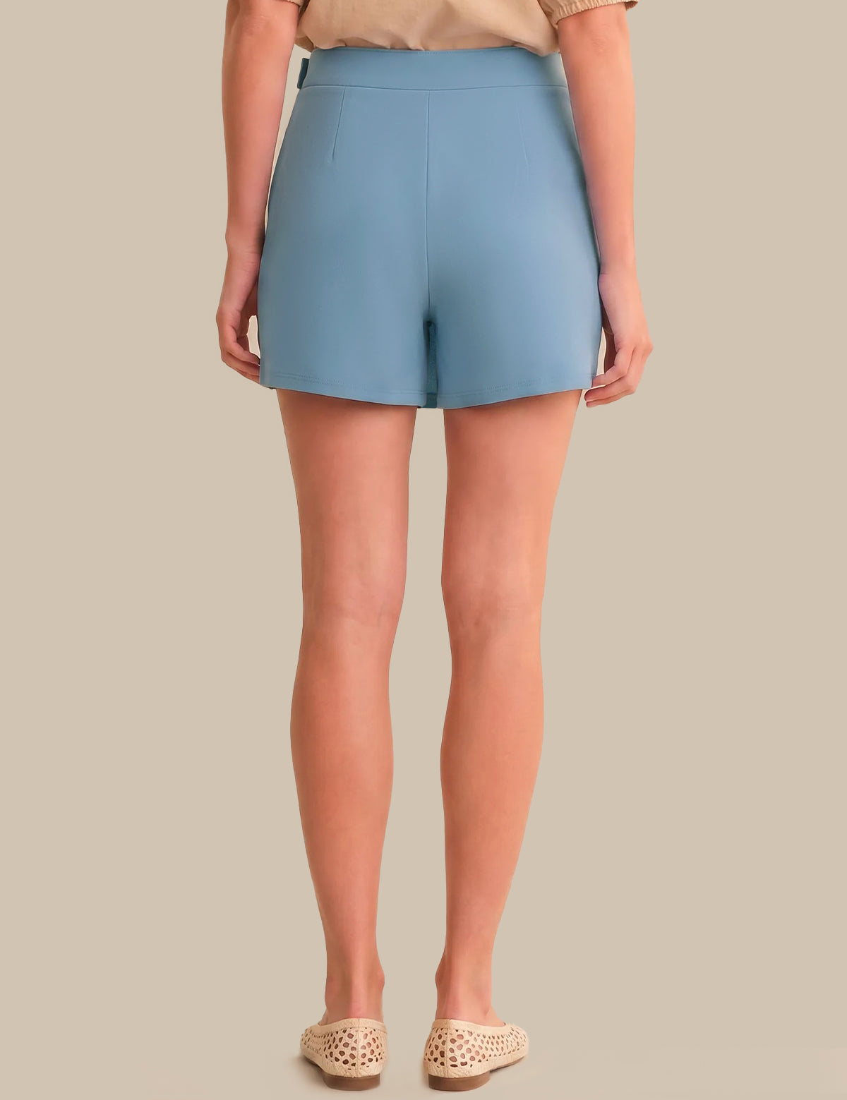Person wearing light blue skort on a beige background