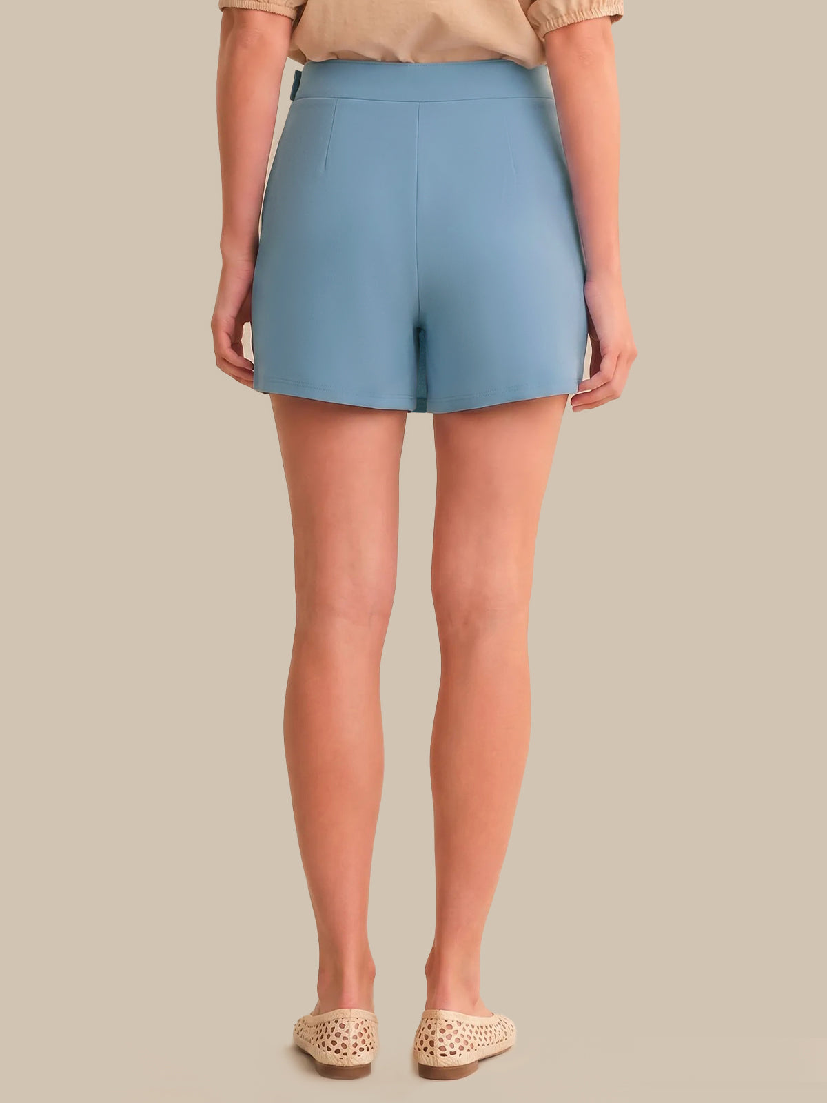 Person wearing light blue skort on a beige background