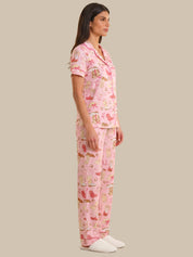 Woman wearing a pink pajama set with animal print on a beige background