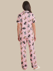 Person wearing pink pajama set with dog print on a beige background