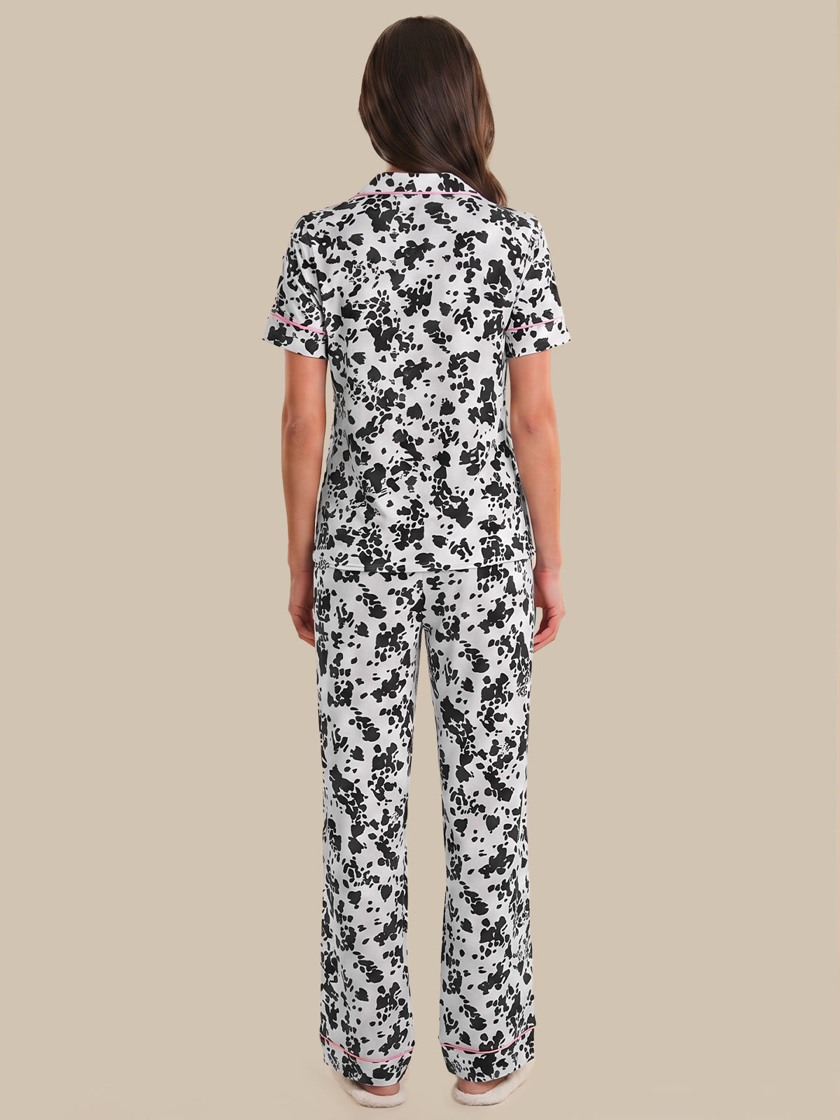 Person wearing a black and white floral pajama set on a beige background