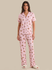 Woman wearing a pink pajama set with a pattern on a beige background