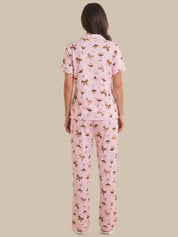 Woman wearing a pink pajama set with a pattern on a beige background
