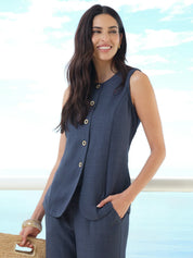 Woman wearing a sleeveless navy top and pants with a blurred beach background