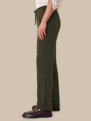 Person wearing olive green pants with a plain background