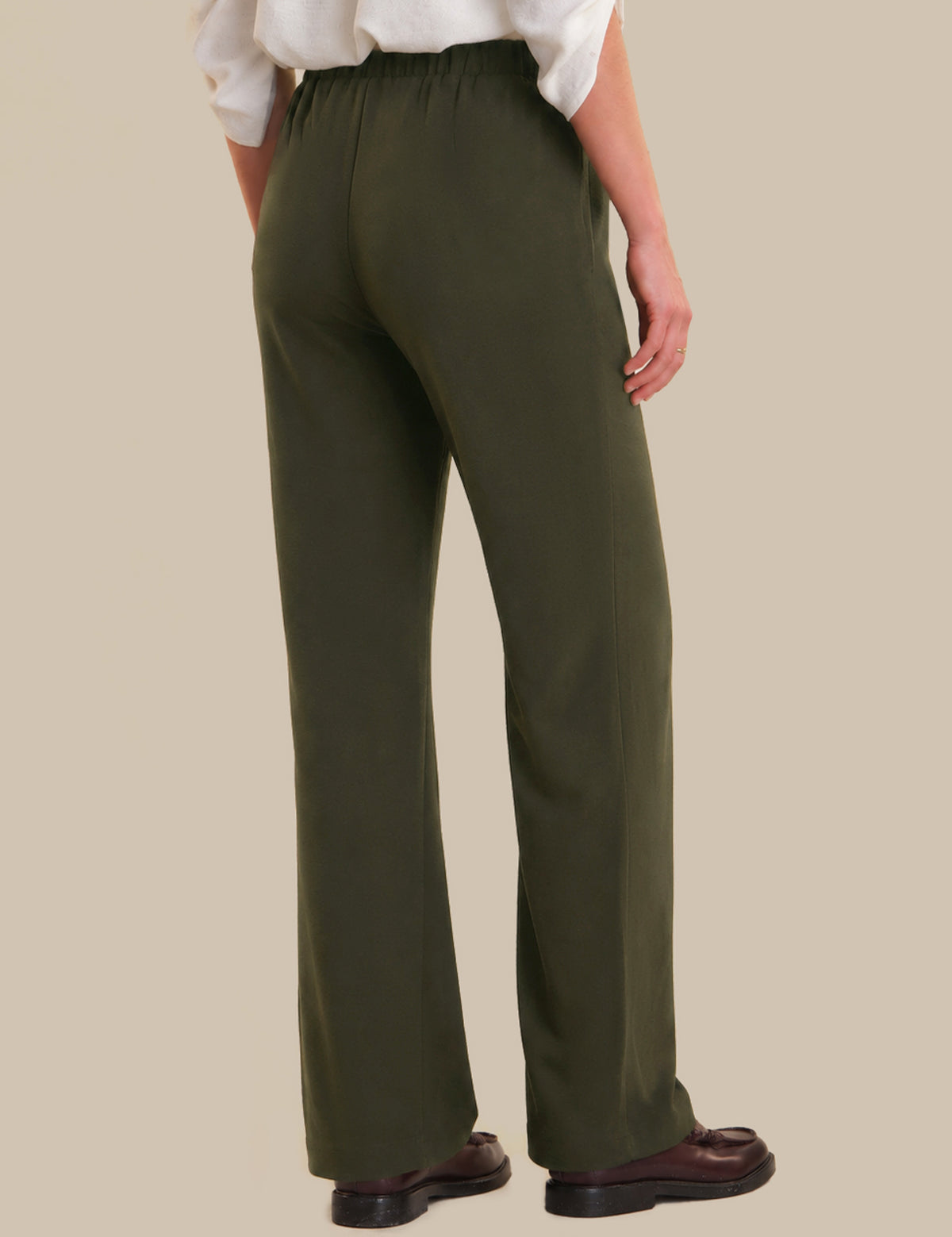 Person wearing olive green pants on a beige background
