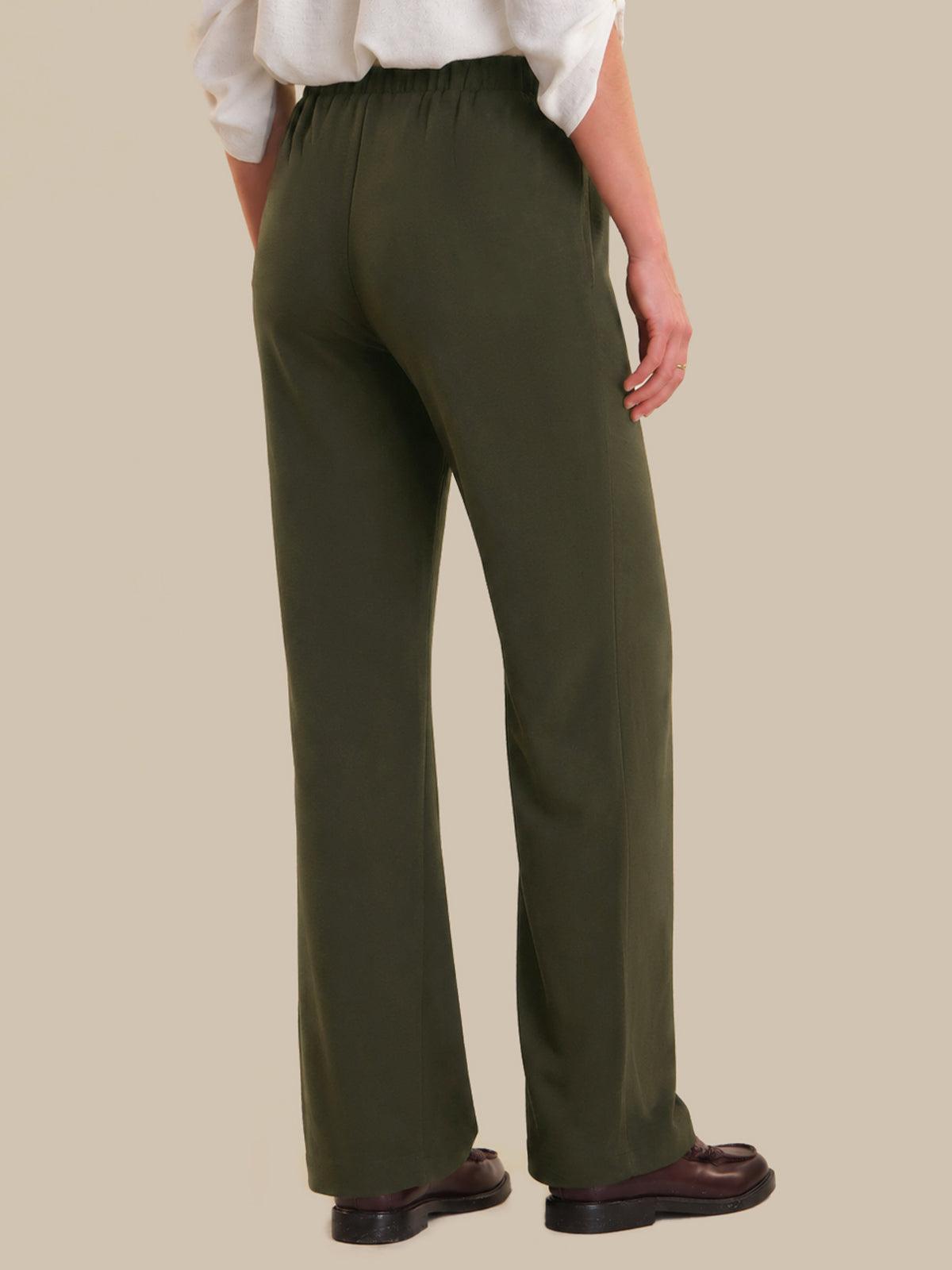 Person wearing olive green pants on a beige background