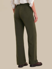 Person wearing olive green pants on a beige background