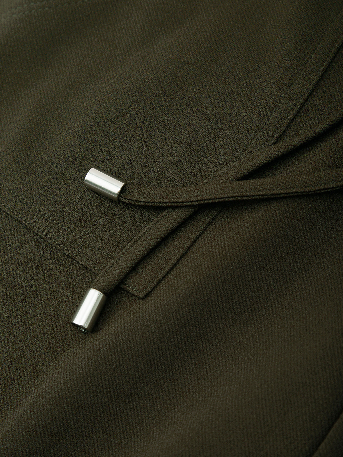 Close-up of a dark green fabric with metal buttons on a plain background