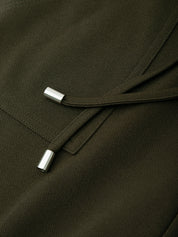 Close-up of a dark green fabric with metal buttons on a plain background