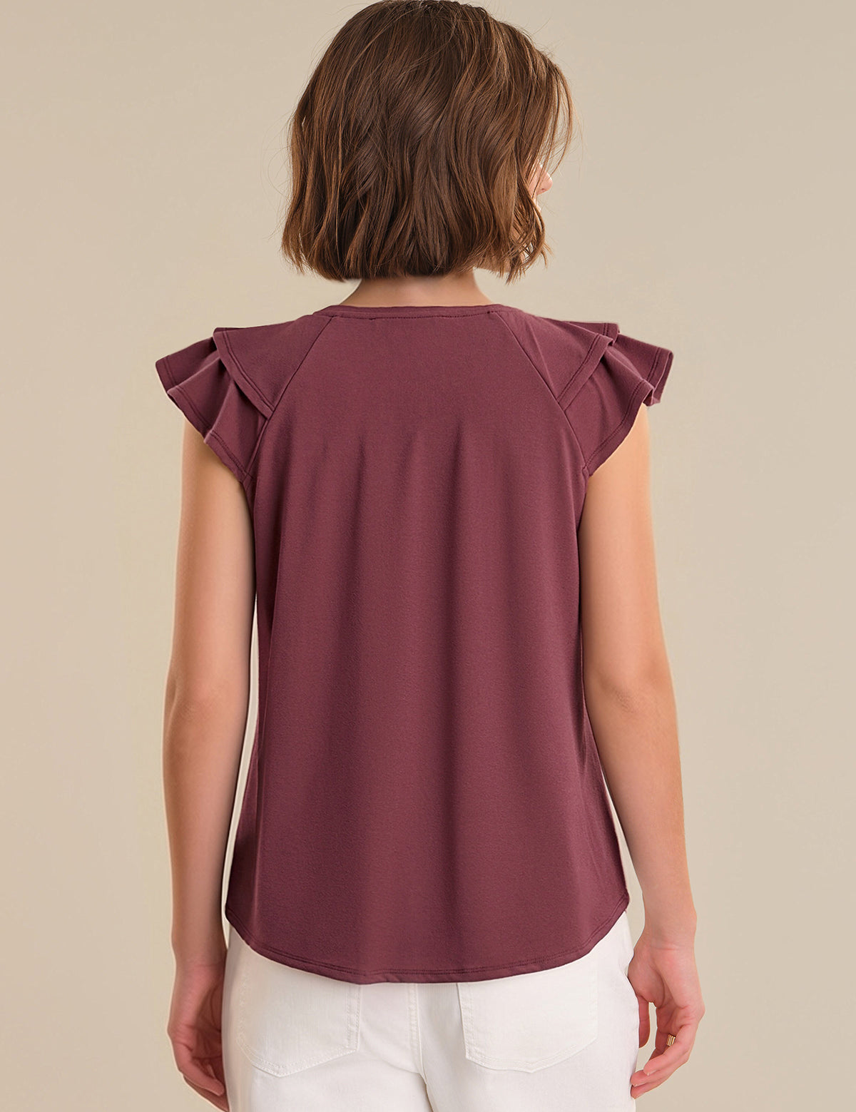 Person wearing a burgundy top with ruffled shoulders on a beige background