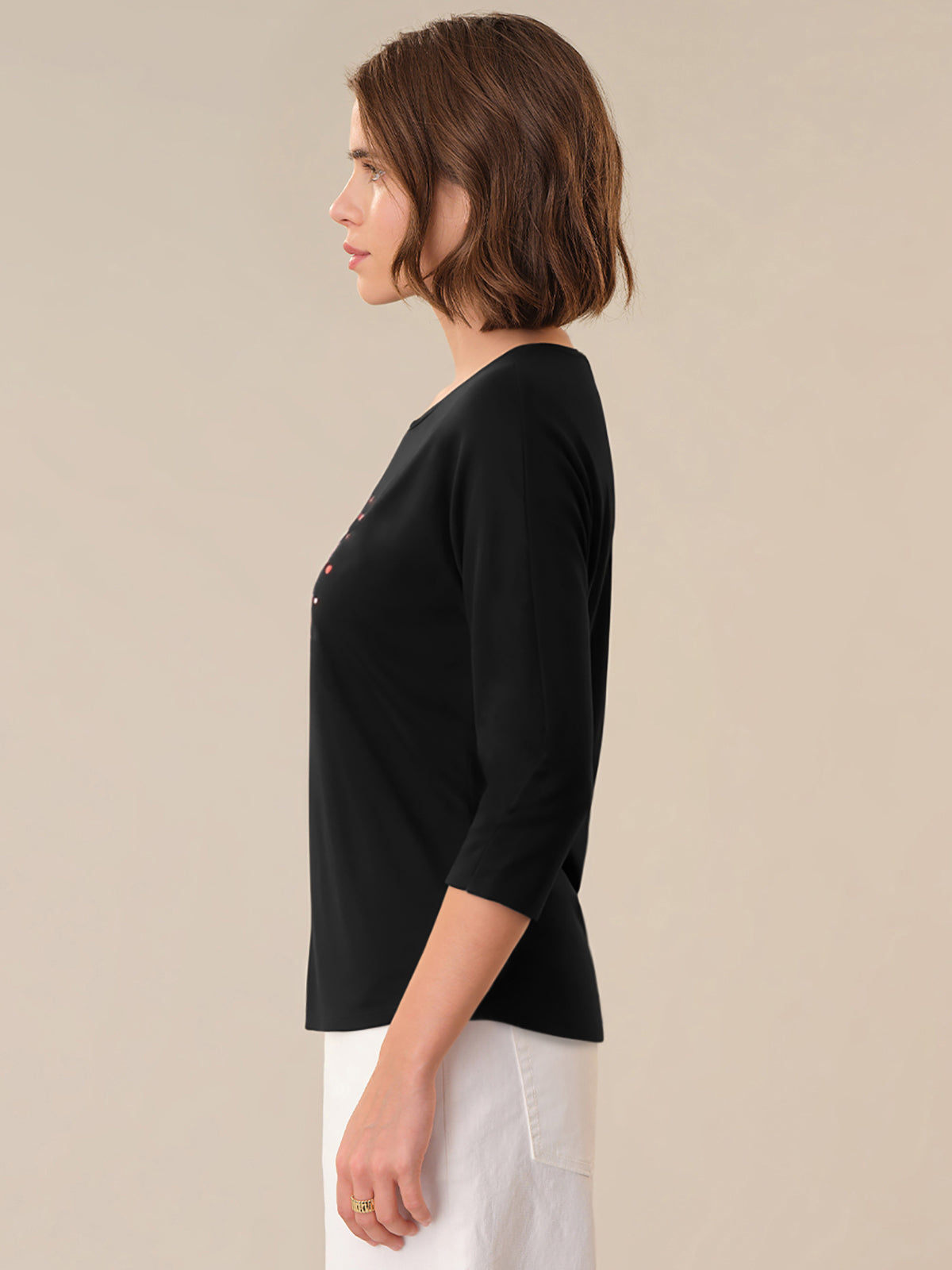 Woman wearing a black top with a subtle pattern on a beige background