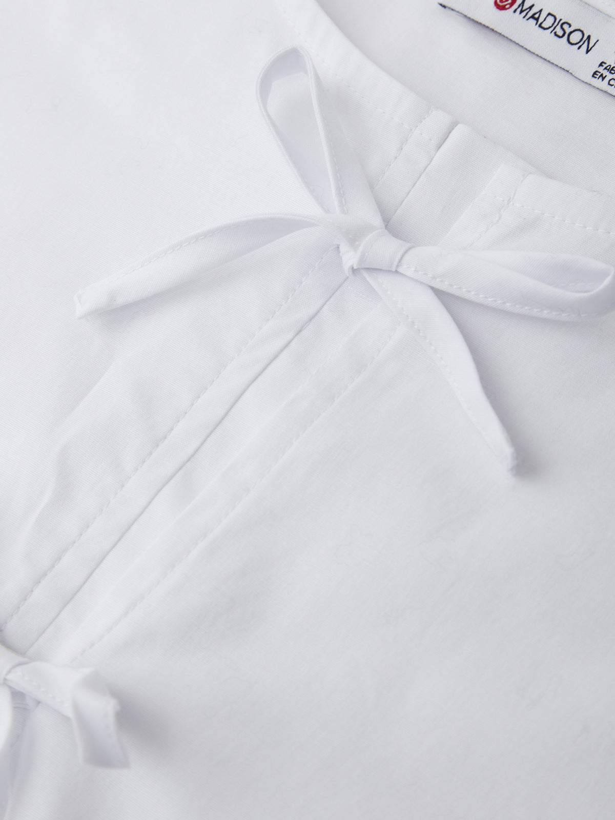 White shirt with a bow tie and 'Madison' label on a white background