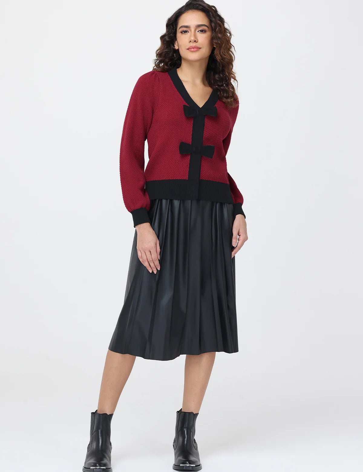 Woman wearing a red cardigan with black accents and a black skirt on a white background
