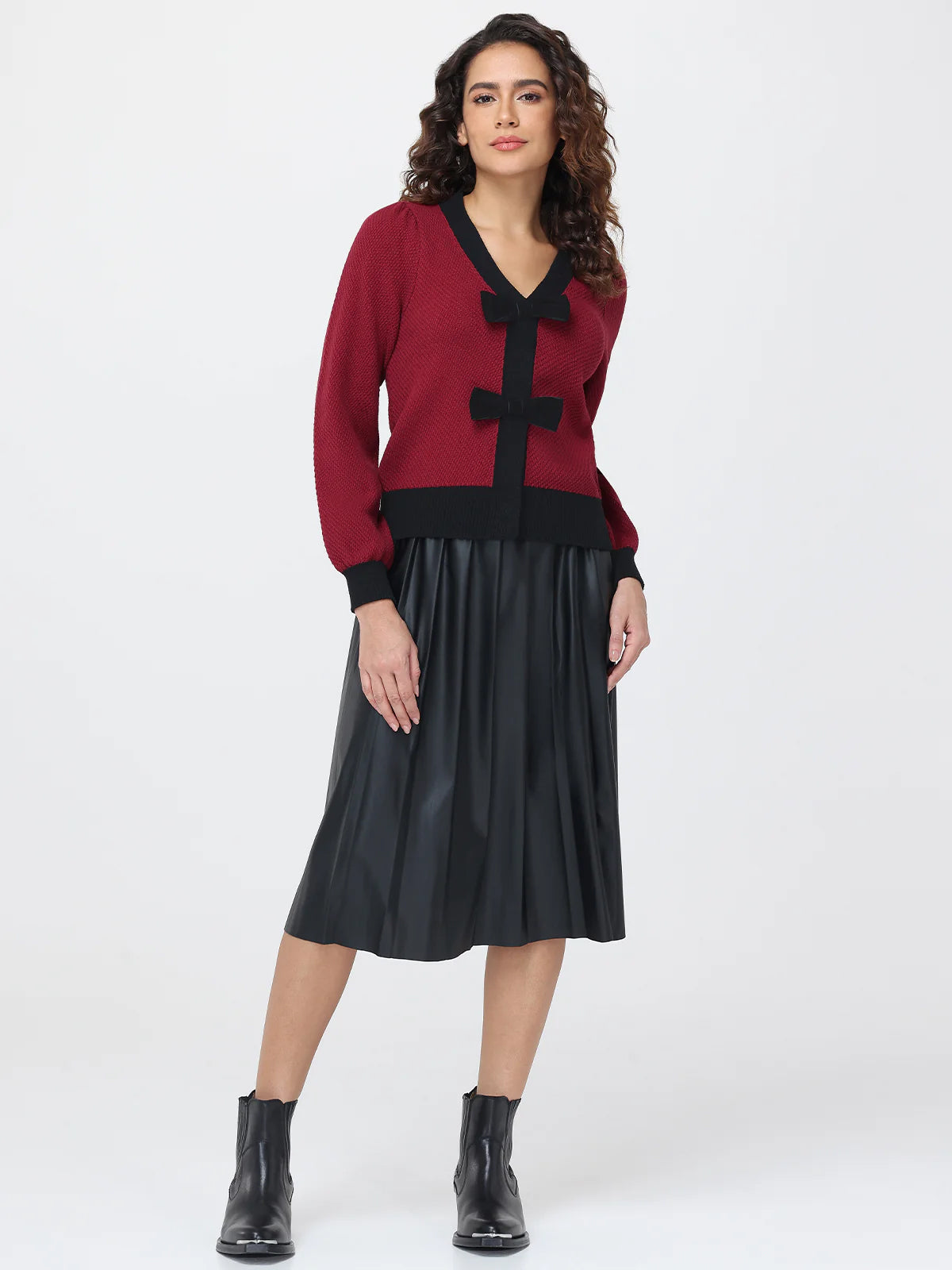 Woman wearing a red cardigan with black accents and a black skirt on a white background